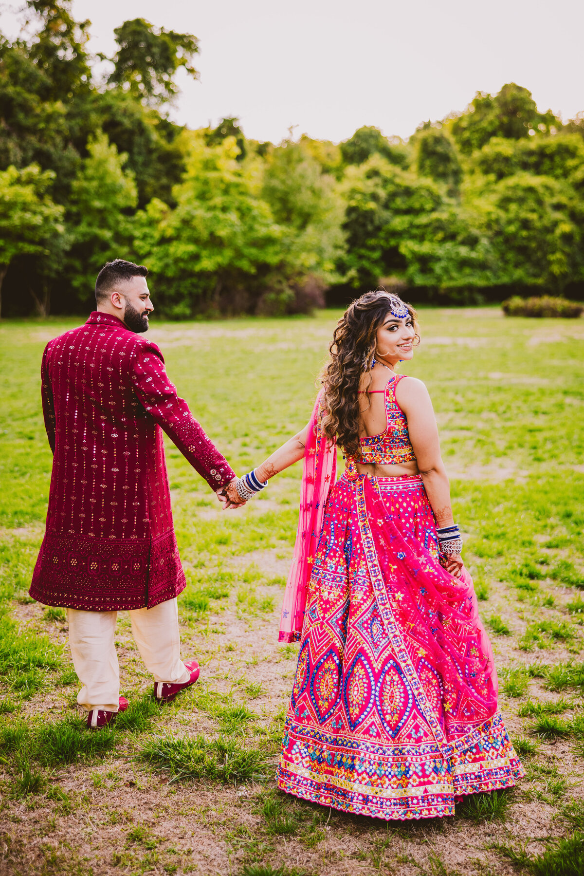 indian bride looking back at the camera as she walks with the groom before the sangeet garba wedding event