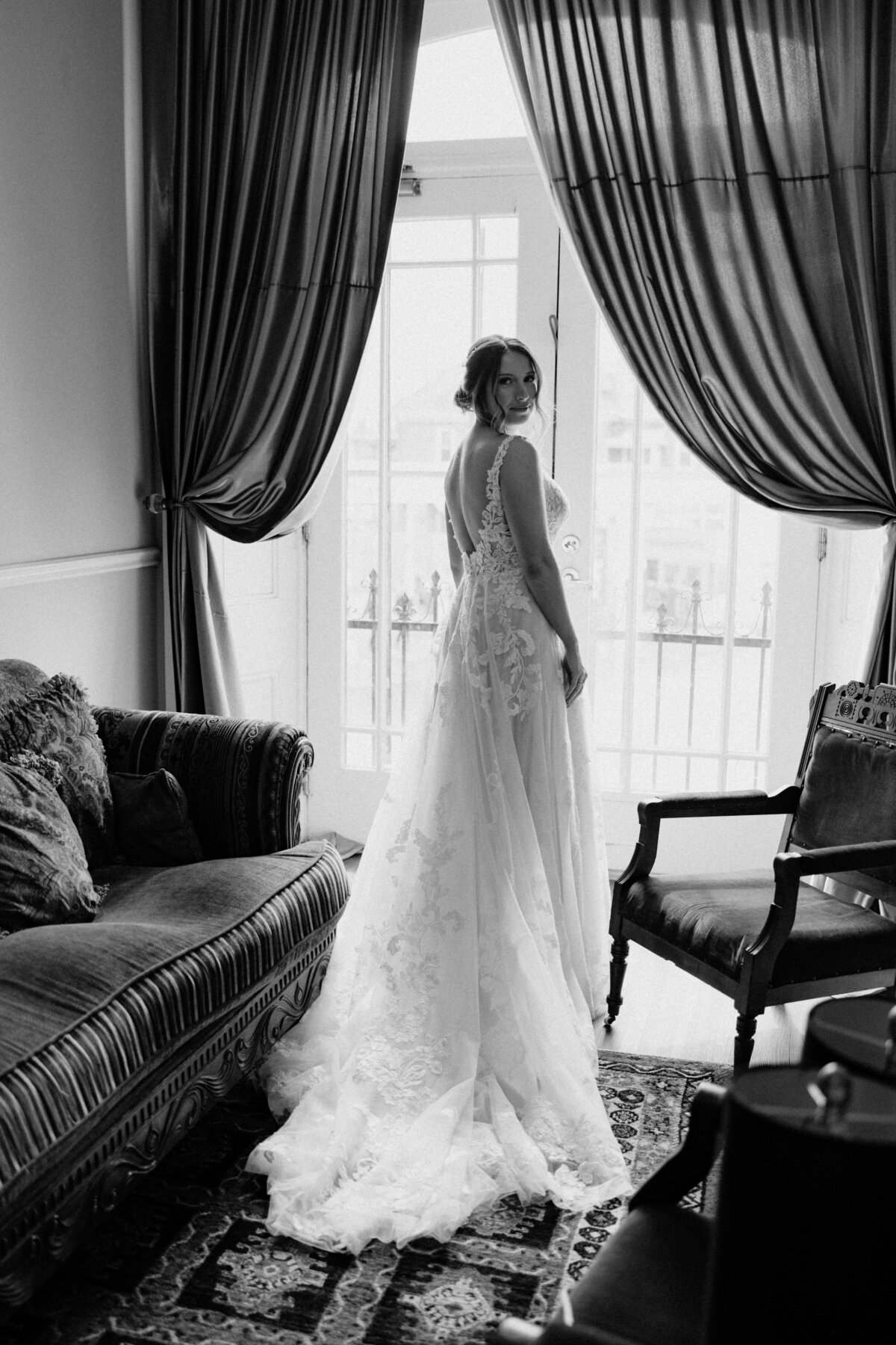 A black and white, looking over the shoulder pose of the bride in her wedding gown