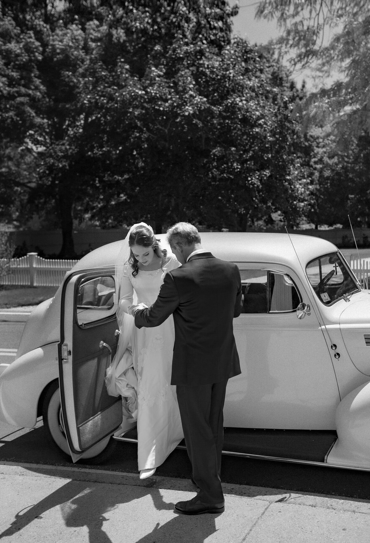 Father helps Bride of out vintage car as they arrive to wedding ceremony.