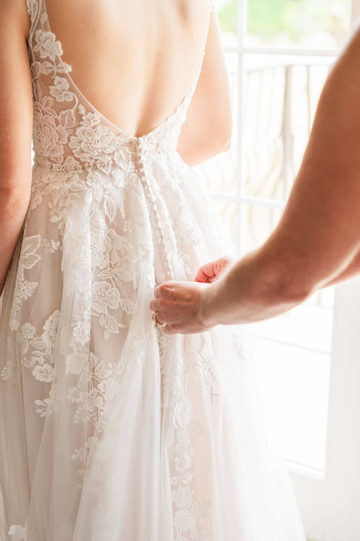 A person helping button up a wedding dress