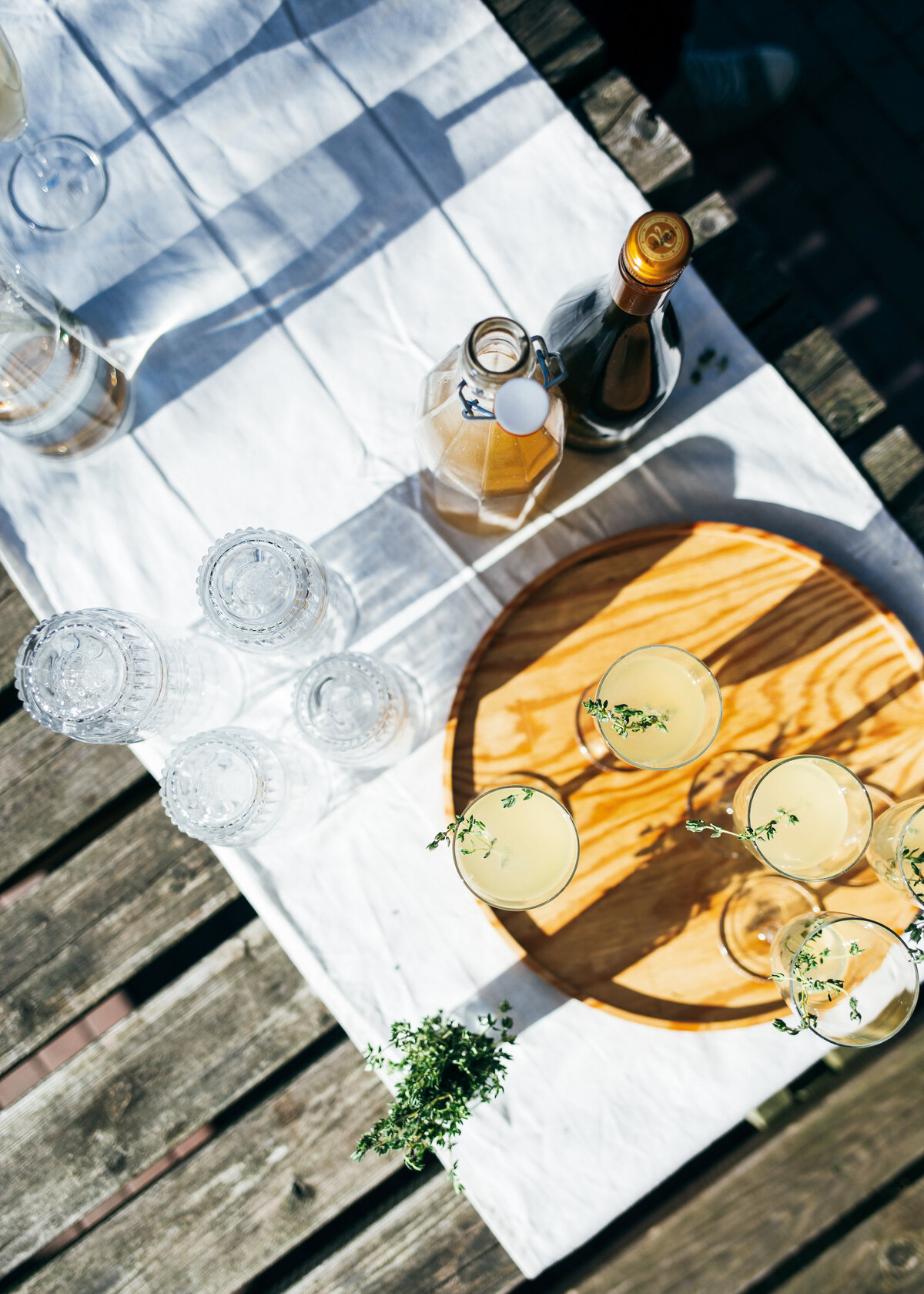 Some cocktails on a wooden tray outside in the sunshine for a garden party or garden wedding.