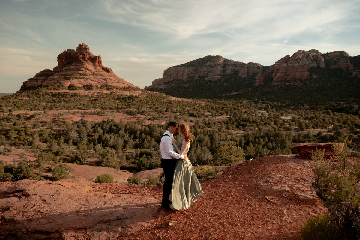 Couple standing against red rock backdrop during Sedona engagement session