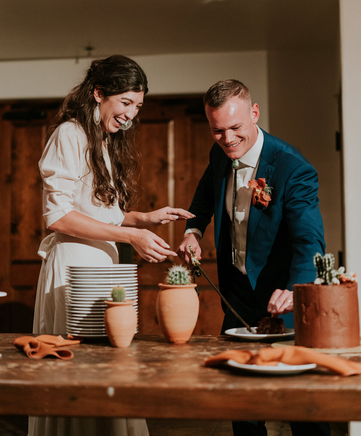 Bride and groom cut their terracotta colored wedding cake during their wedding reception.