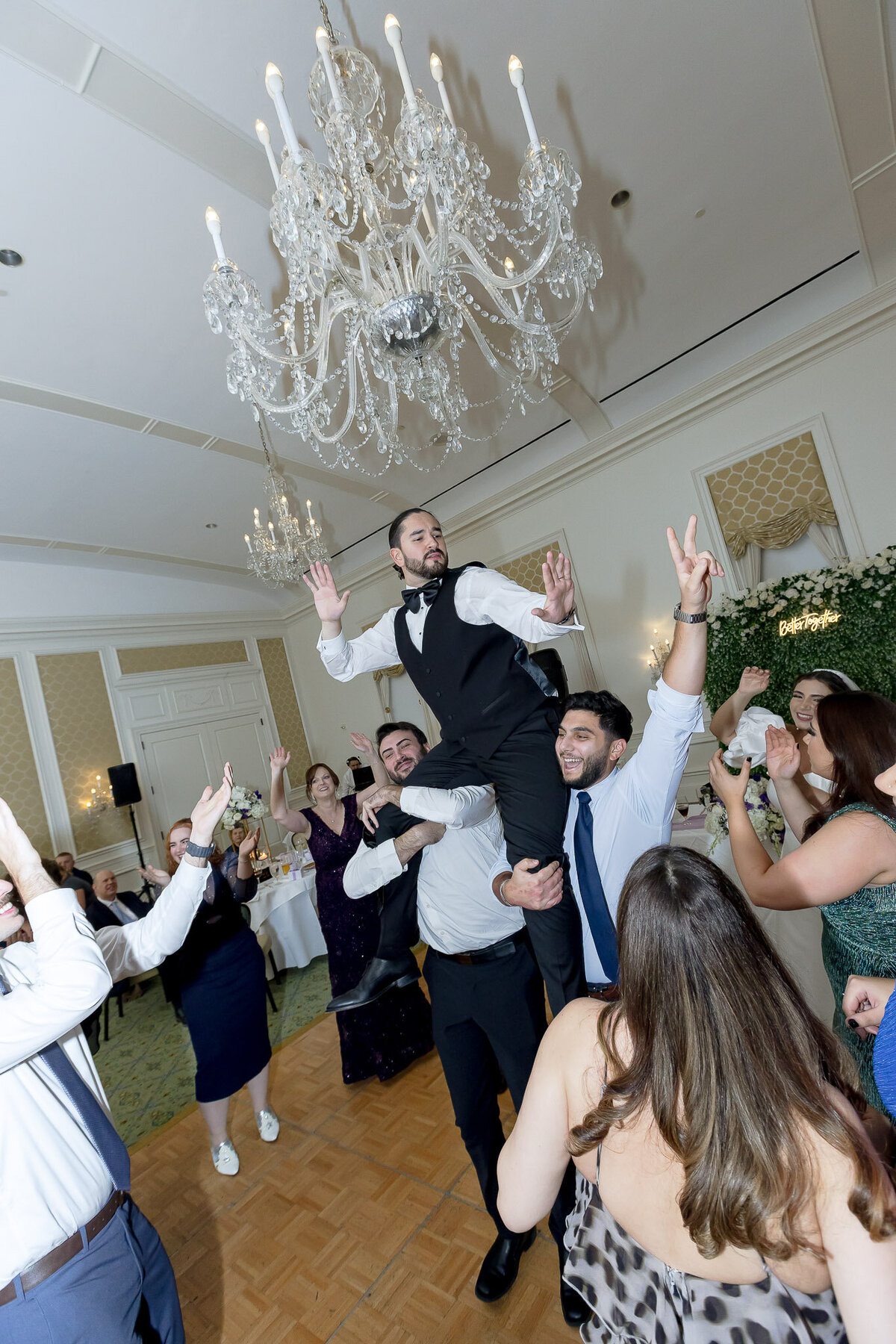 The groomsmen hold the groom during the wedding reception afterparty, carrying him on their shoulders.