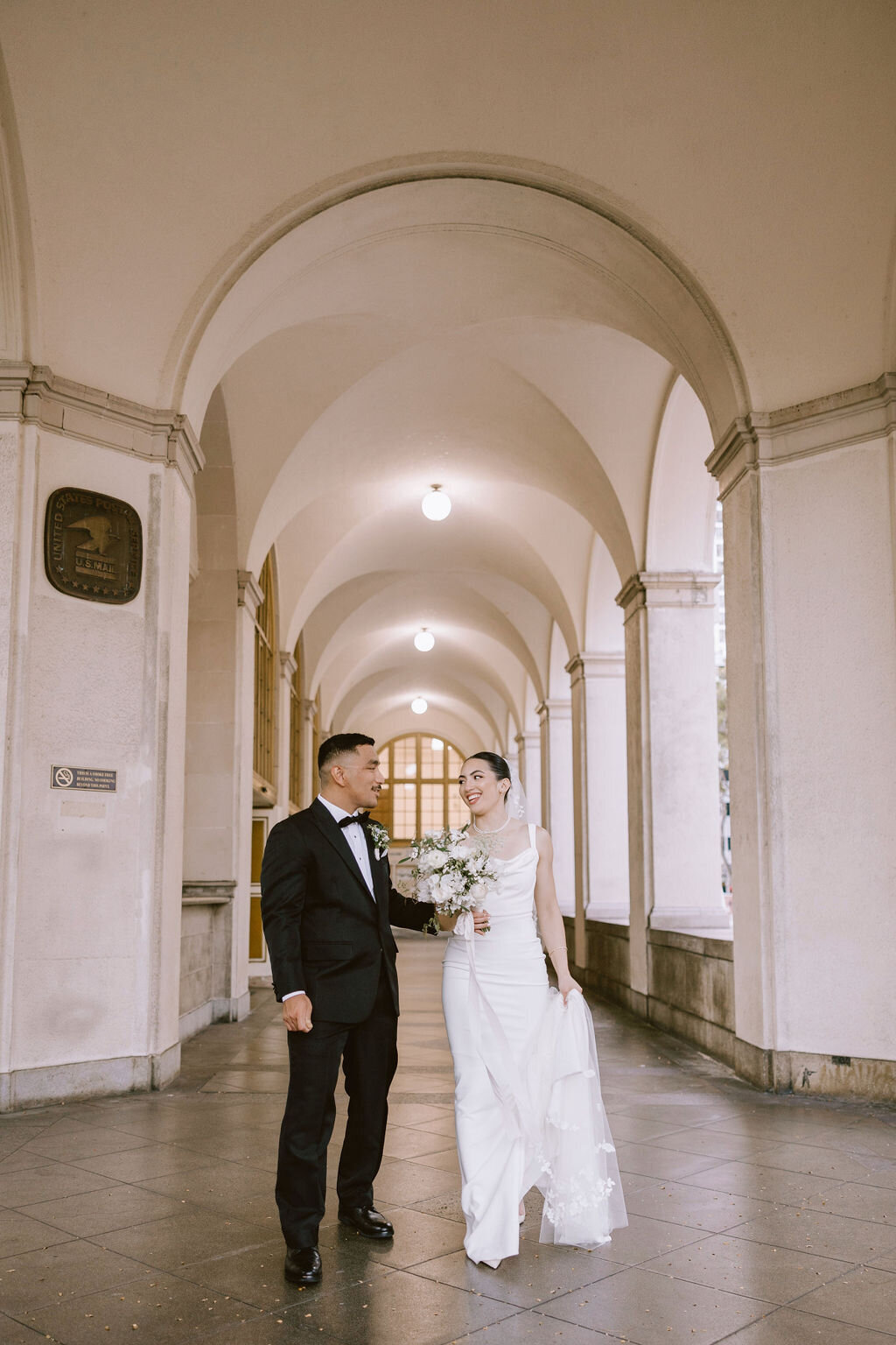 bride and groom under european architecture looking at each other while she carries bouquet