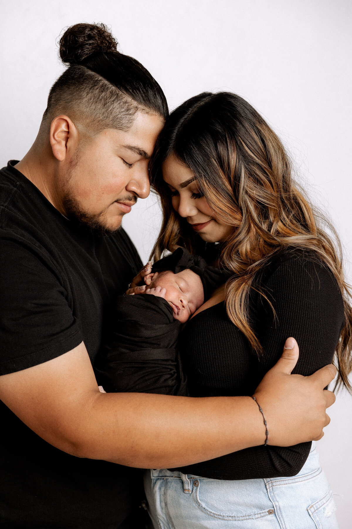lubbock newborn photo of couple hugging baby swaddled in black