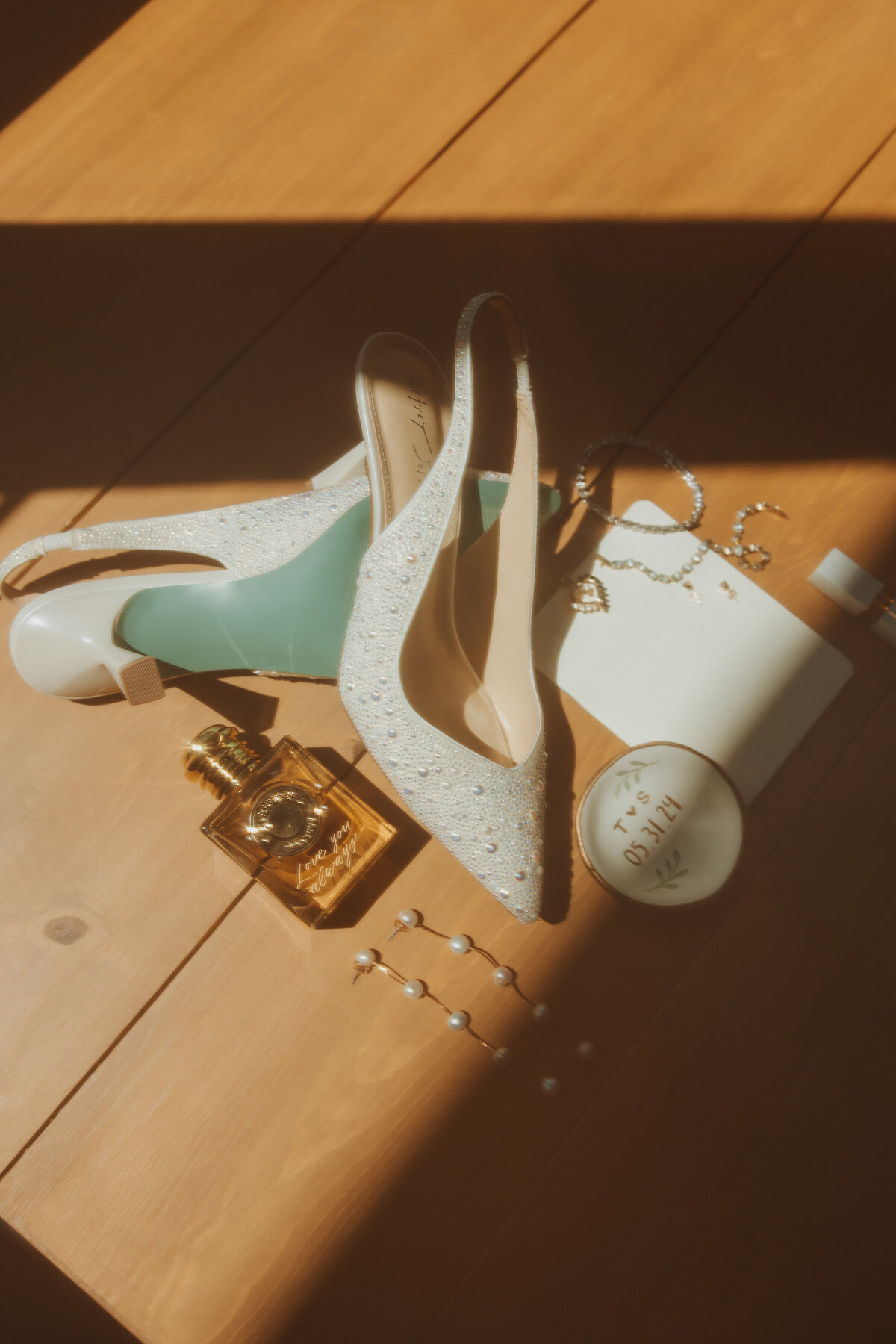 Flatlay of bride’s shoes, perfume, and accessories