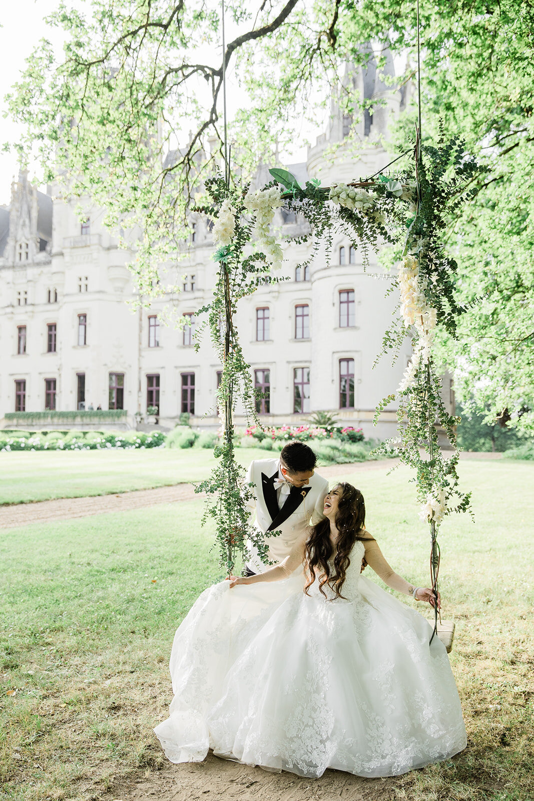 Romantic moment with bride and groom on a swing outside a French château during their elopement