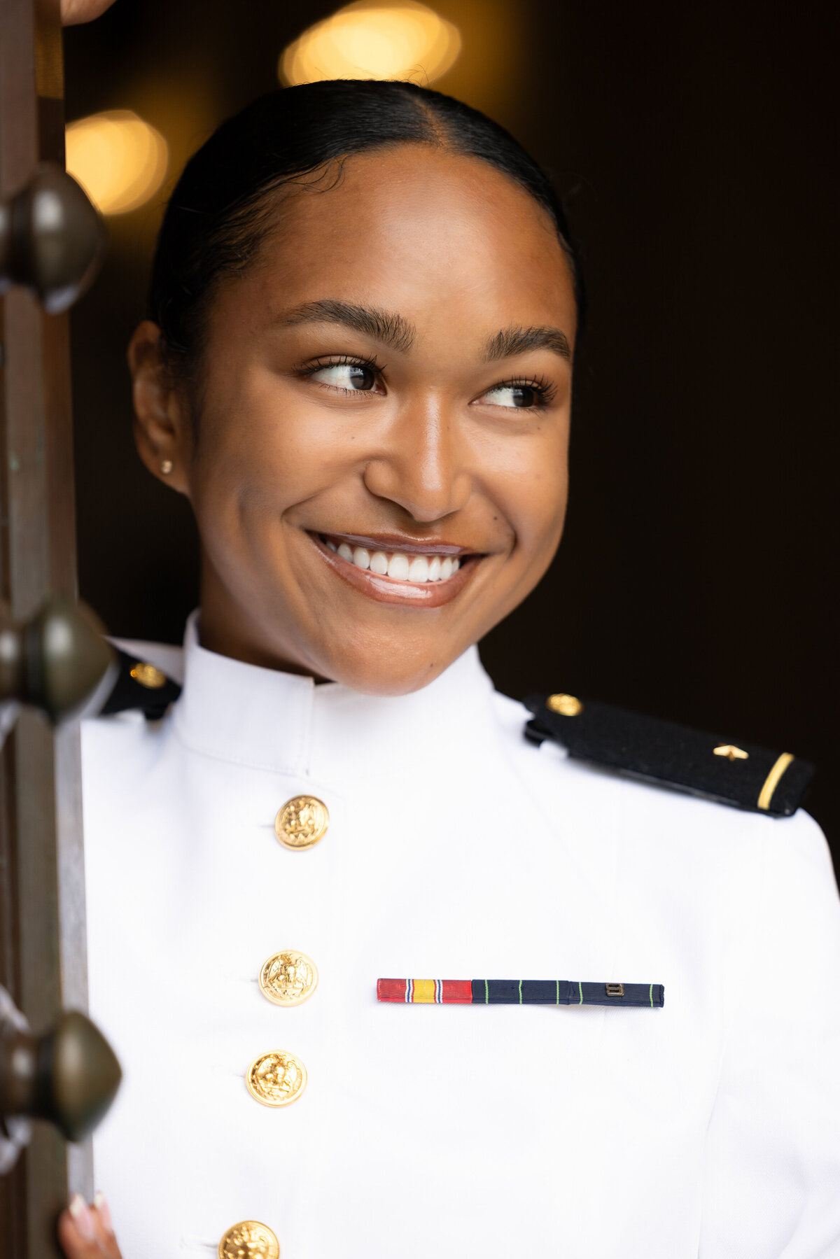 Female U.S. Navy Midshipman smiles and looks off camera near Bancroft Hall in Annapolis