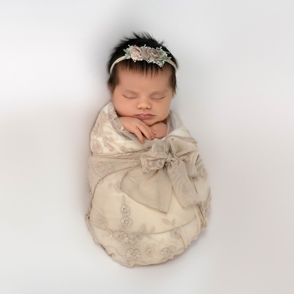 newborn girl in beige wrap