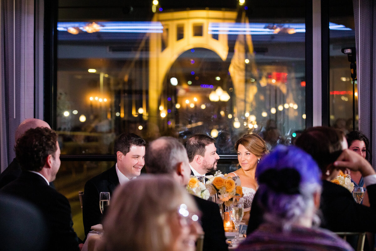 wedding photo inside of the ballroom at renaissance pittsburgh with the roberto clemente bridge visible through the window behind the couple