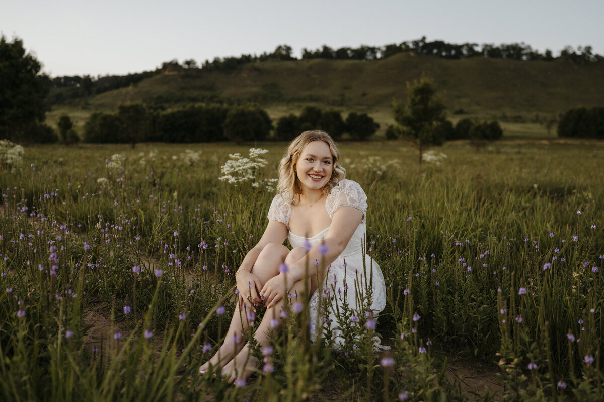 Girl sitting in flower field in white dress