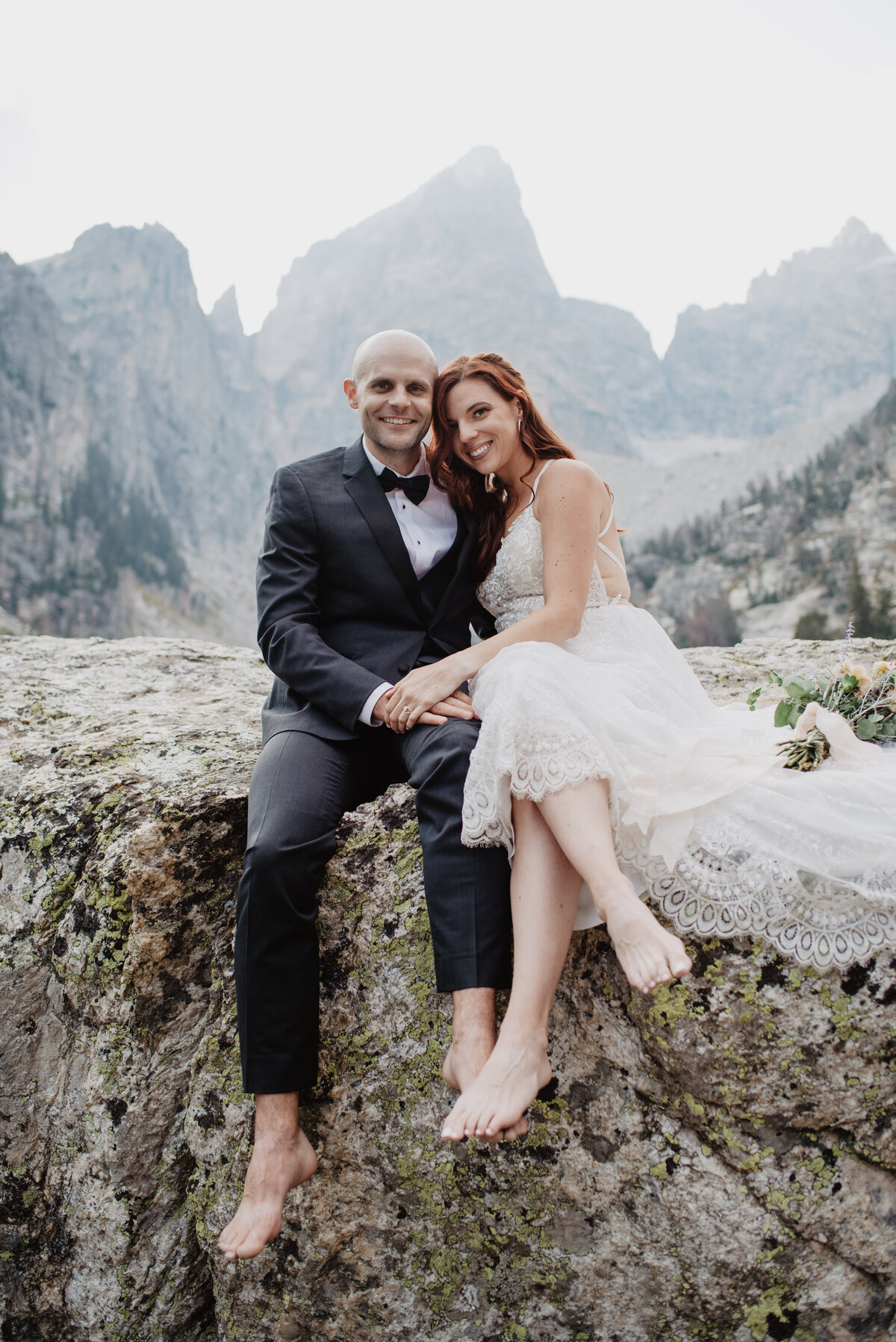 Jackson Hole Photographers capture Grand Teton elopement with bride and groom hugging on boulder