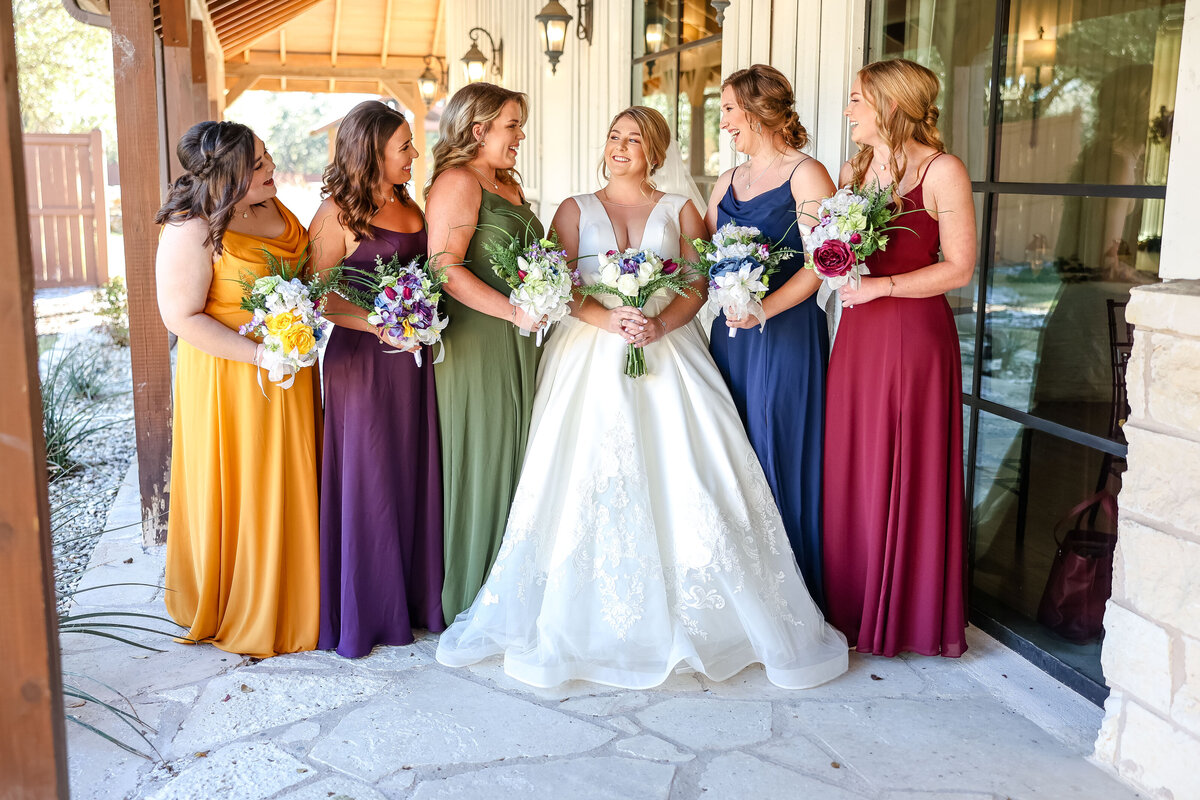 bridesmaids in multiple colors surround bride at wedding near Austin Texas
