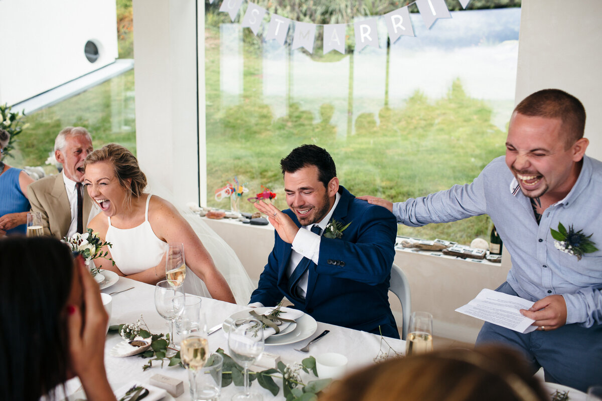 Couple laughing hard at the Best man's speech at their Cornish Wedding 