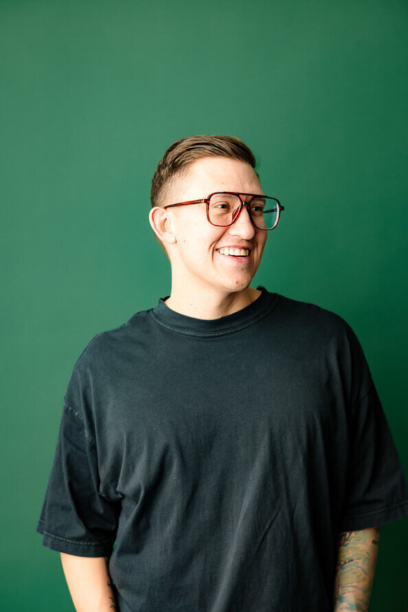 Man in glasses and green shirt smiles off to side.