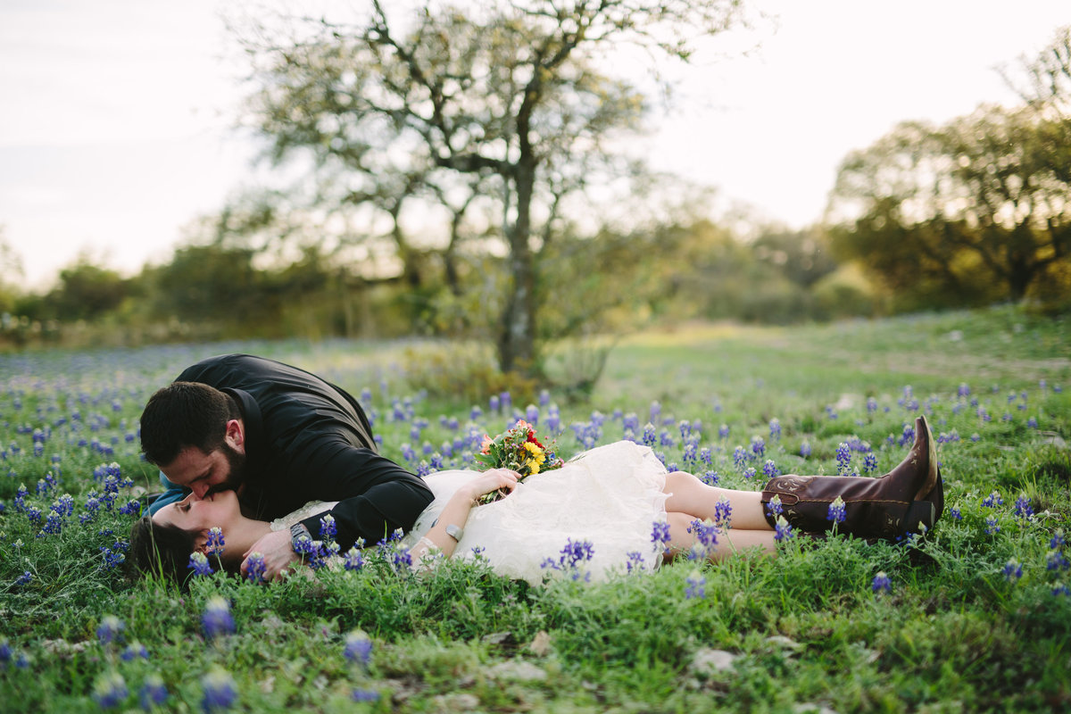 Bride and Groom laying in Bluebonnets at Hofmann Ranch wedding venue by San Antonio Wedding photographer Expose The Heart