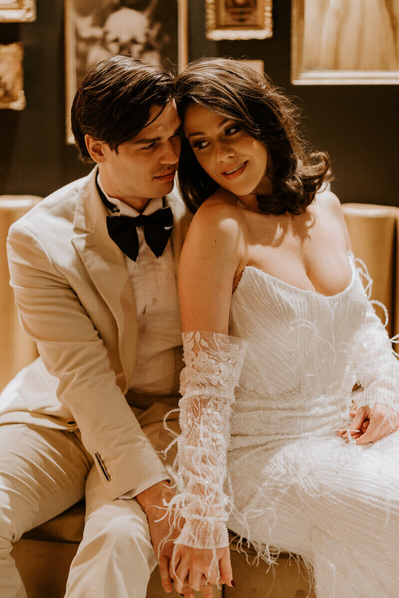 Mariés assis l'un contre l'autre dans un décor vintage pour une séance photo mariage.