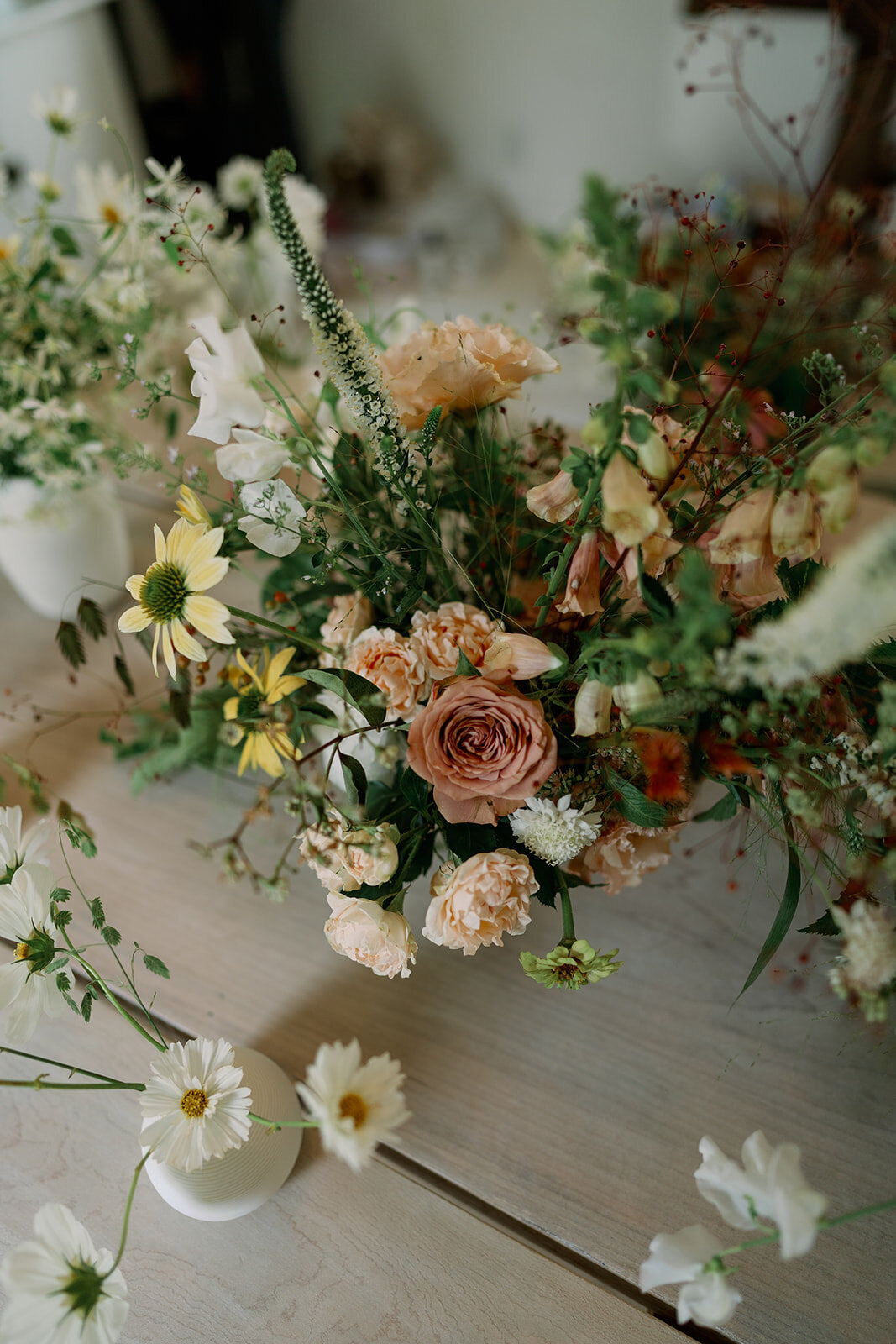 Romantic blush, ivory, and peach floral centerpiece captured during the reception at Glasshouse Community in Ottawa County.