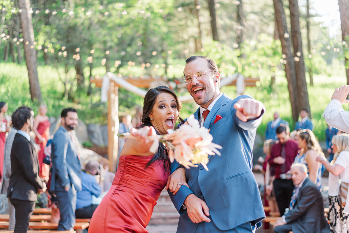 groomsman and bridesmaid celebrate the end of the ceremony and point at the camera