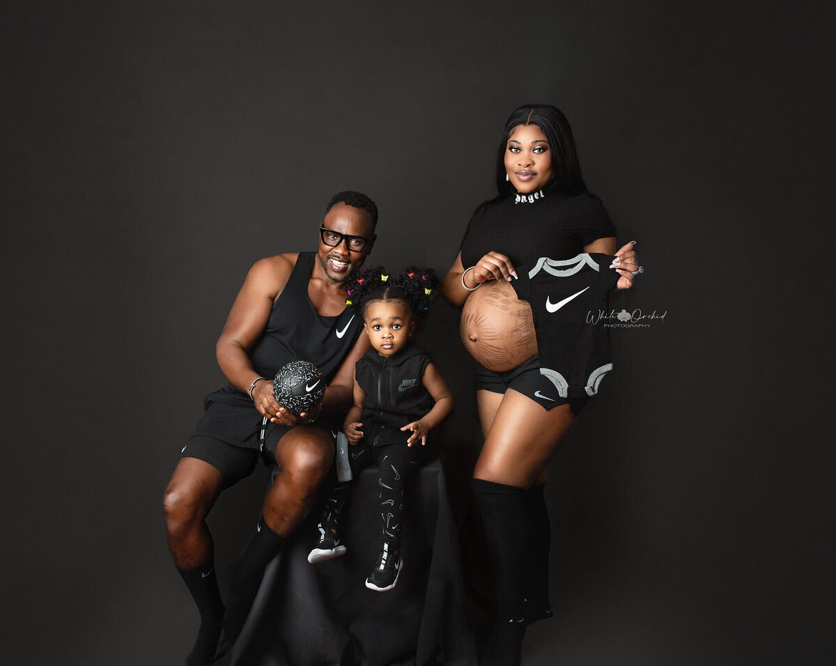 family poses for maternity portrait dressed in nike clothes