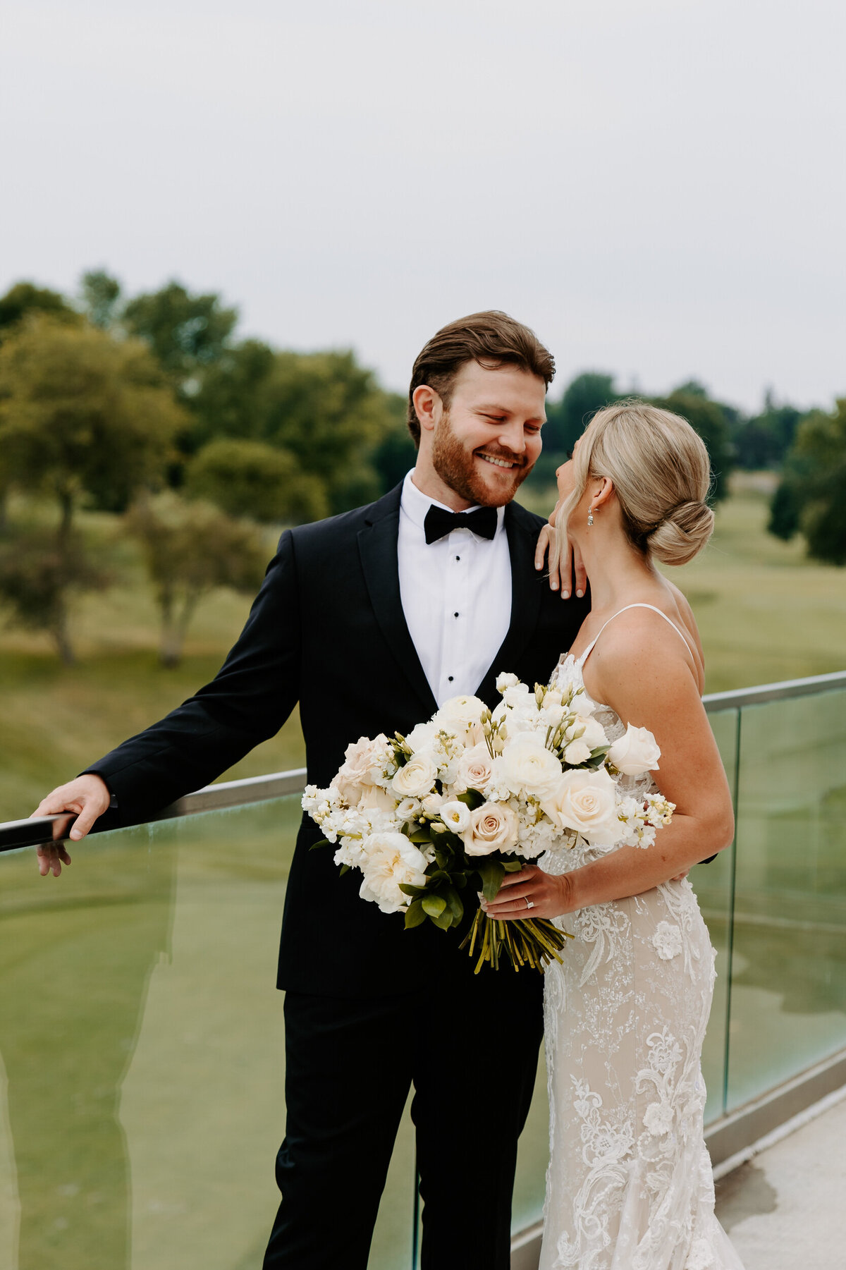Newlyweds standing on a balcony smiling at each other