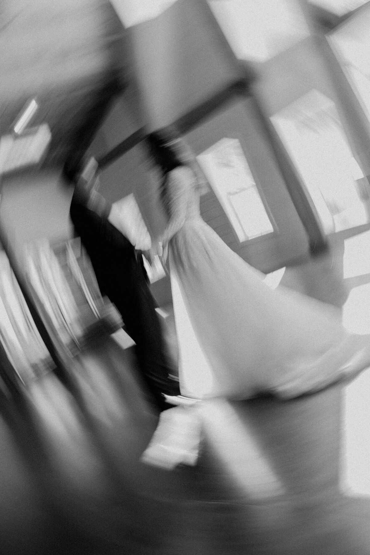 A motion blur photo of a bride and groom dancing in a black and white film style.