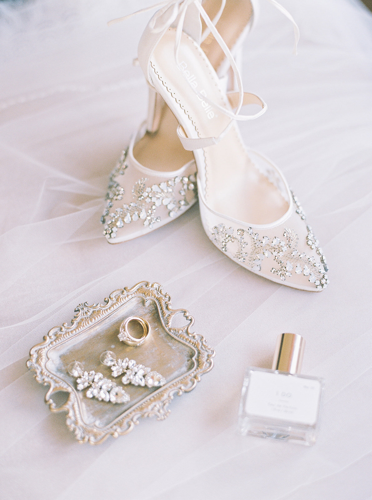 flat lay of white bridal shoes with silver jewelry
