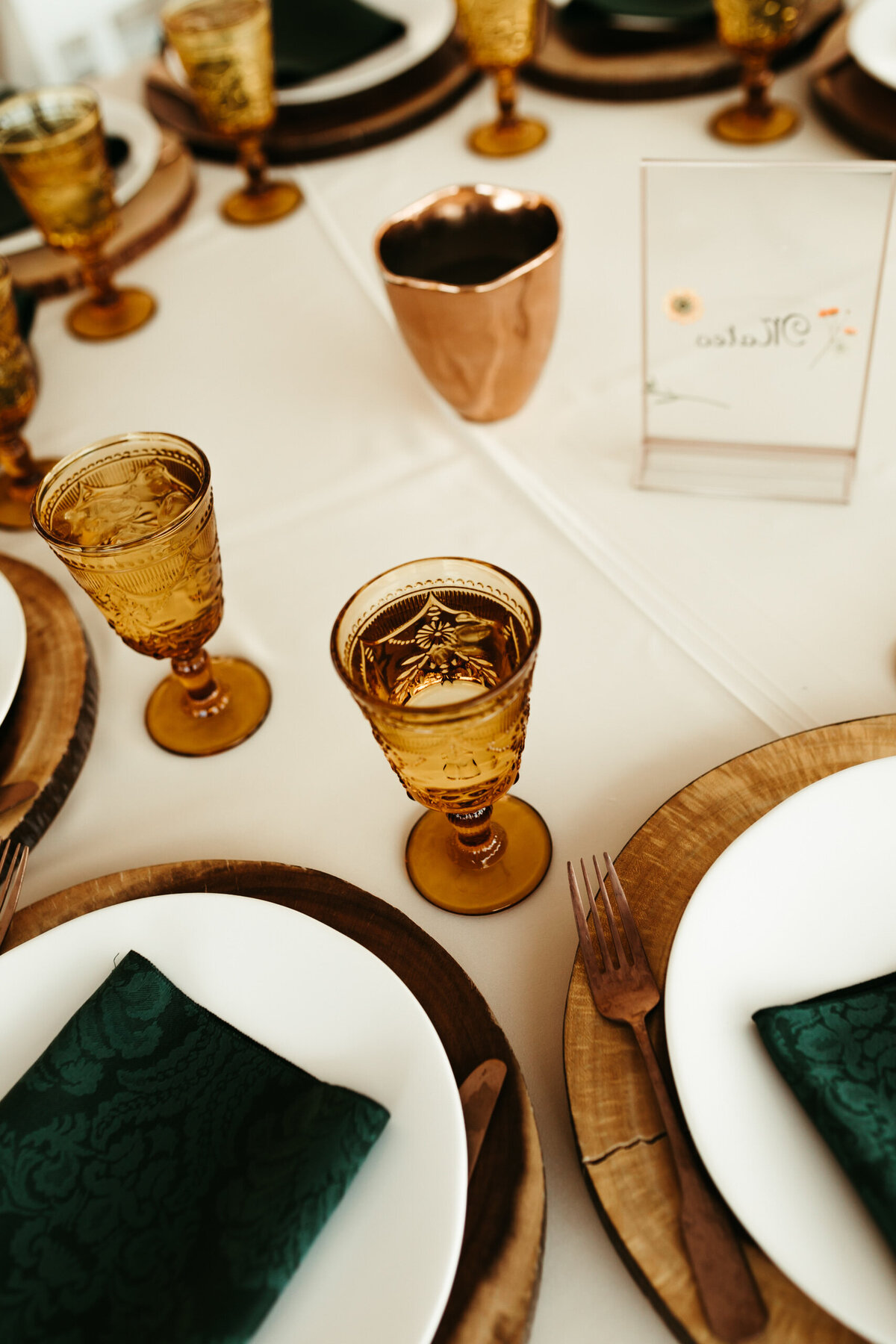 Amber water goblets with green napkins at a wedding reception.