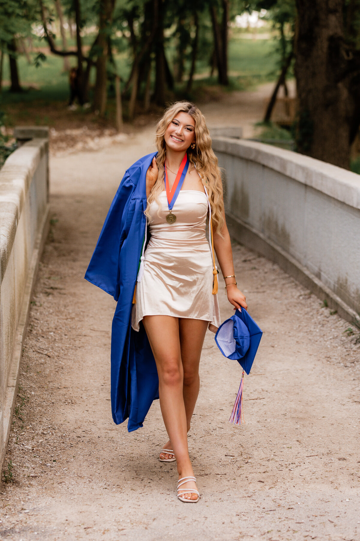 Girl does a runway walk with her graduation gown over her shoulder.