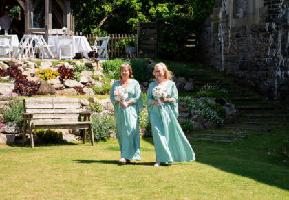 A couple of bridesmaids walking towards the wedding aisle.