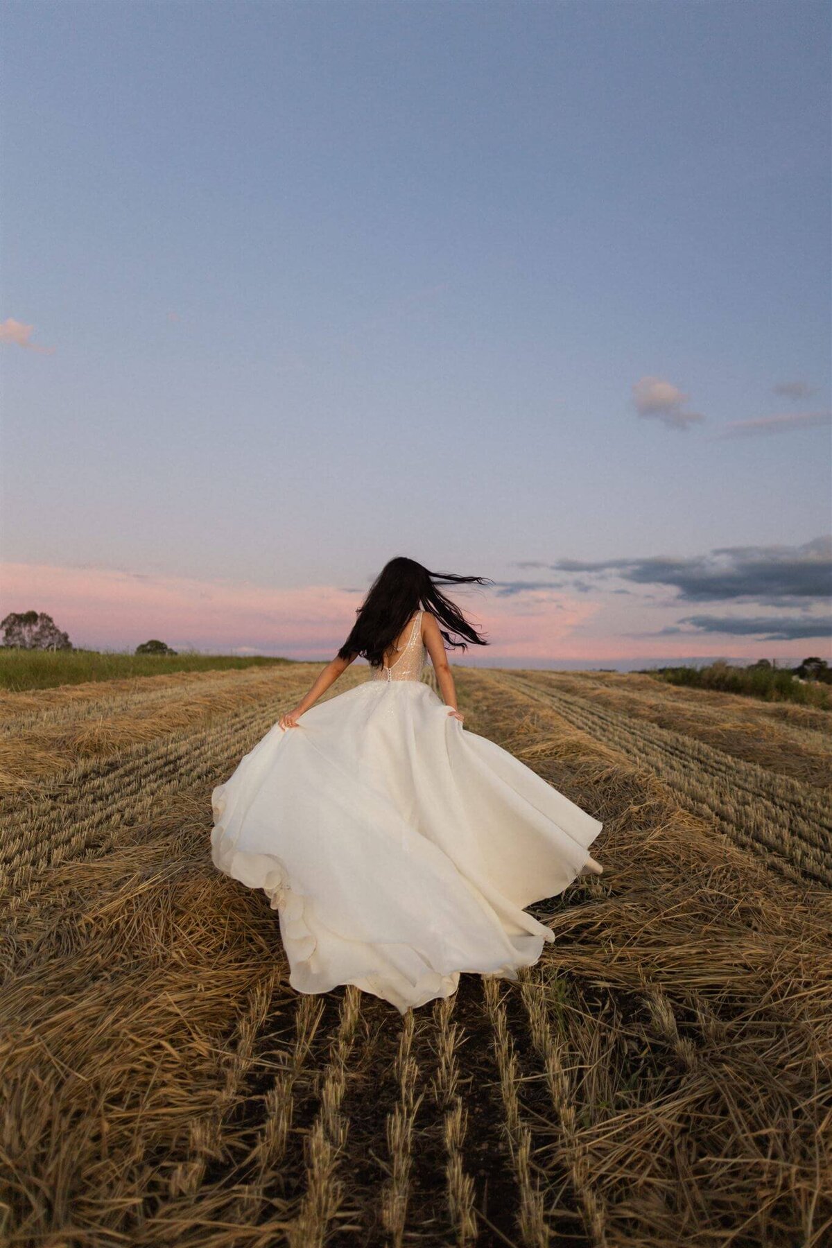 Wedding photo bride running in a field at sunset
