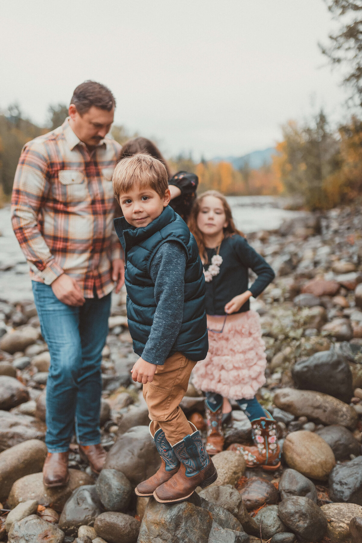 Little boy standing on a river bed with fall foliage