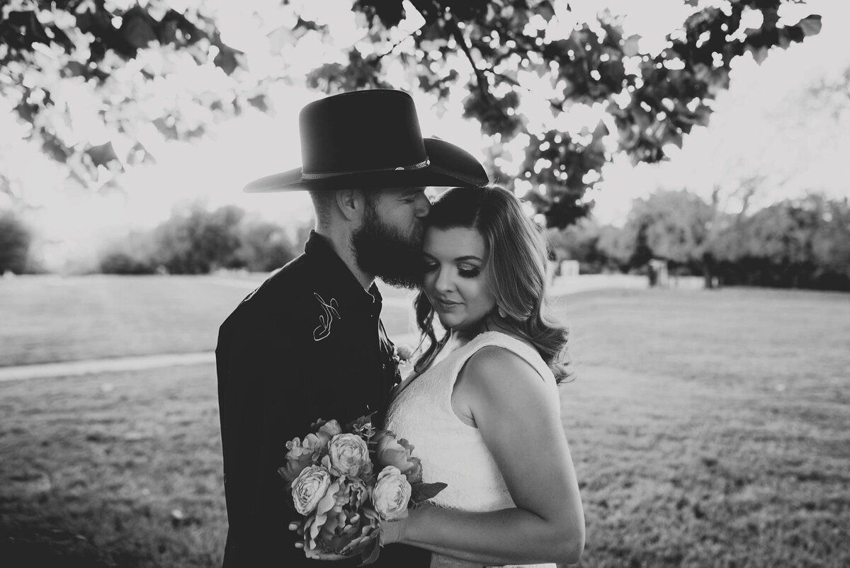 a black and white photo of a newly married couple kissing