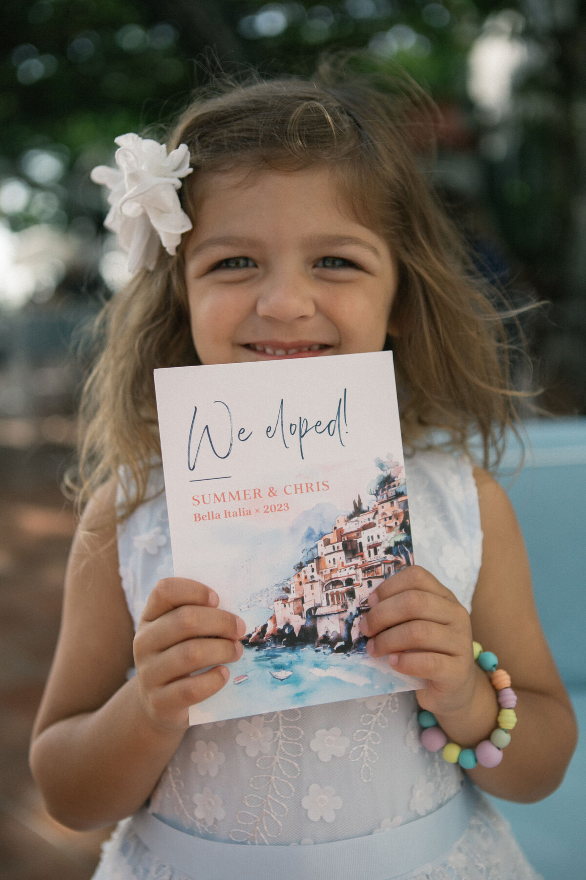 Flower girl holding handwritten wedding note – sweet candid moment from Summer & Chris' Positano elopement