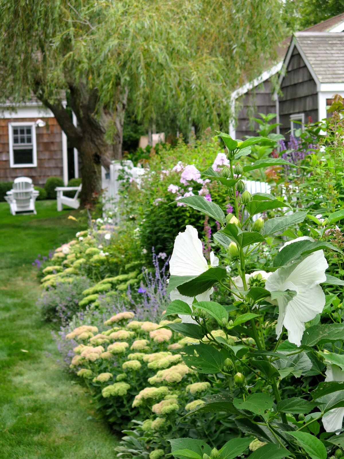 A sloping backyard with a fresh green lawn leading toward a wooded area.