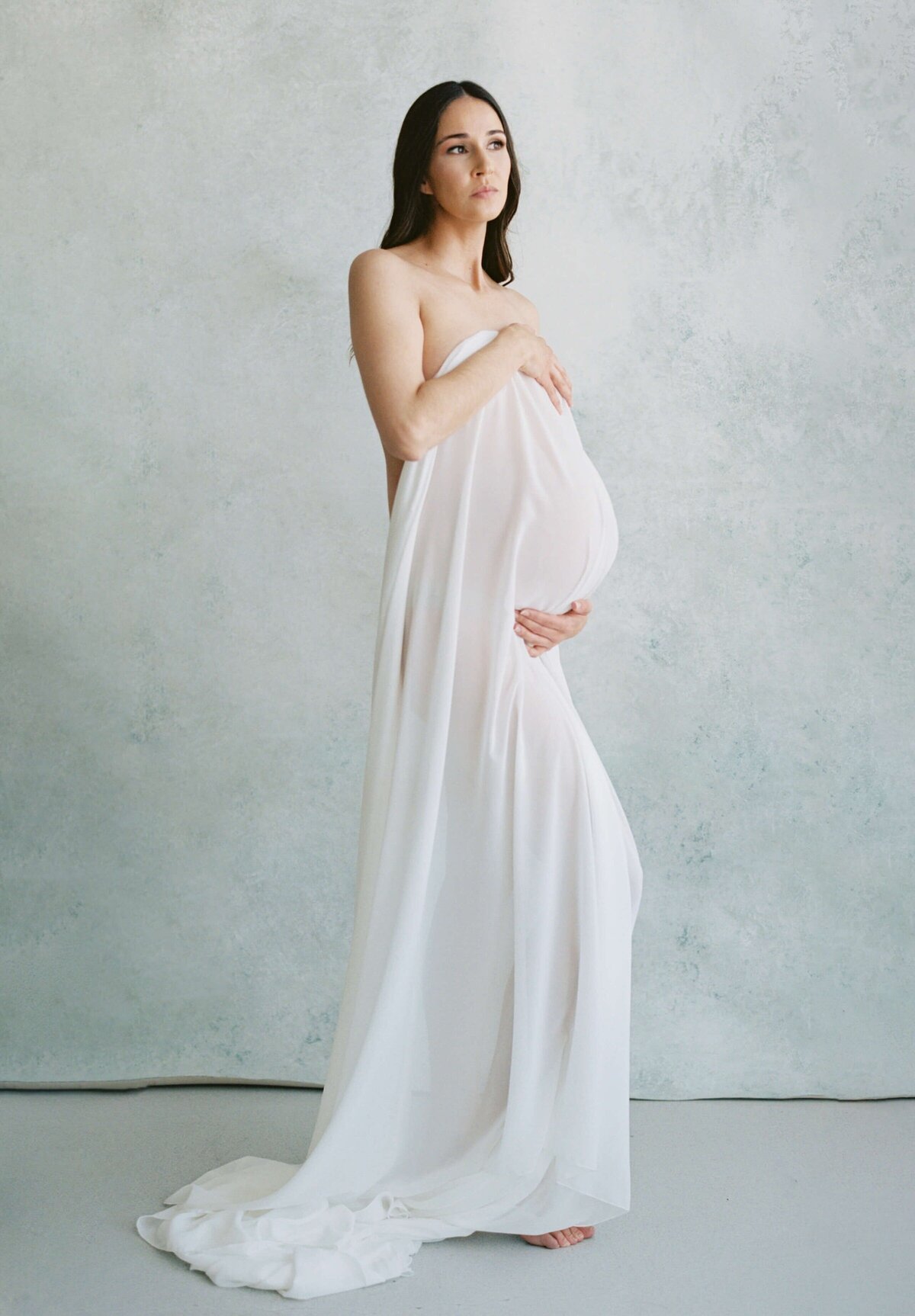 pregnant woman posing in white dress for her studio maternity photos in san francisco