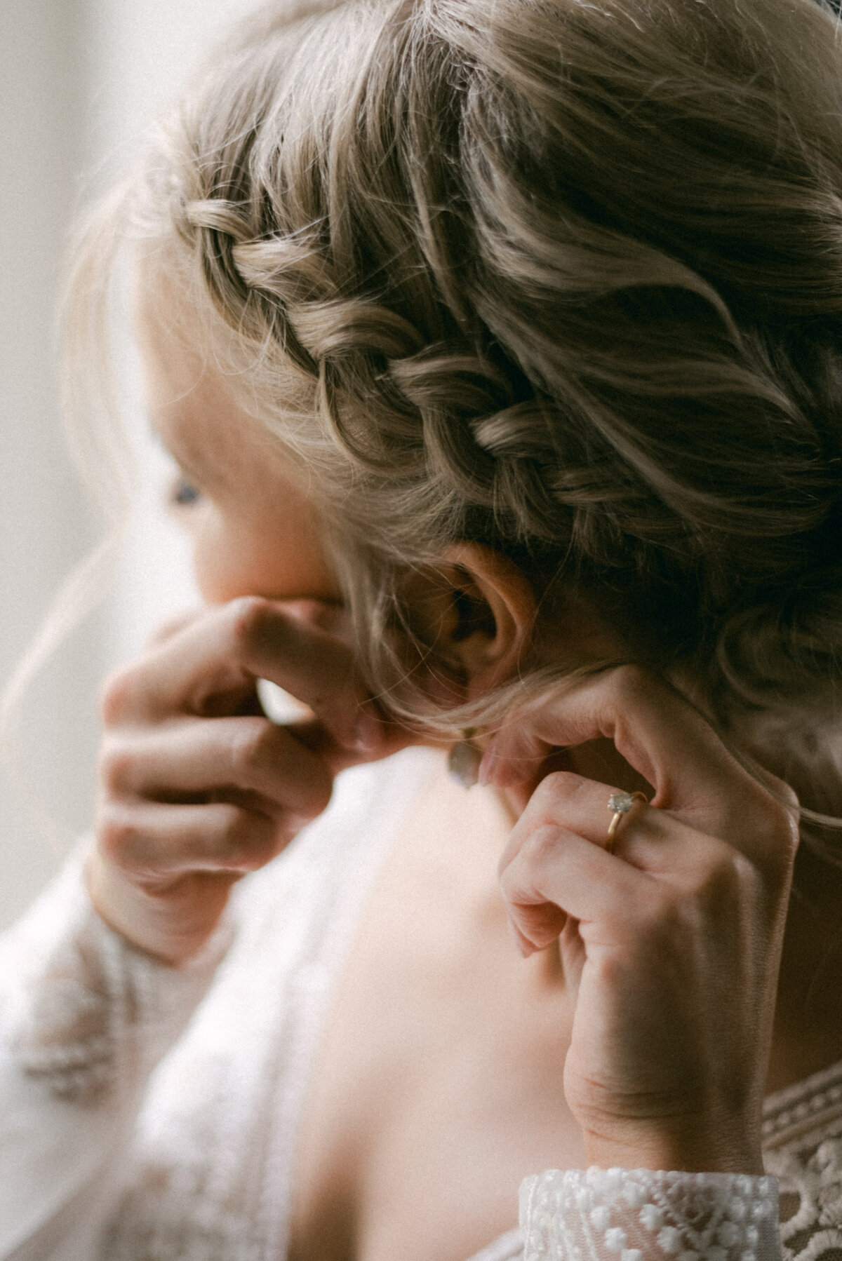 A documentary wedding  photo a bride putting on her earrings in Oitbacka gård captured by wedding photographer Hannika Gabrielsson in Finland