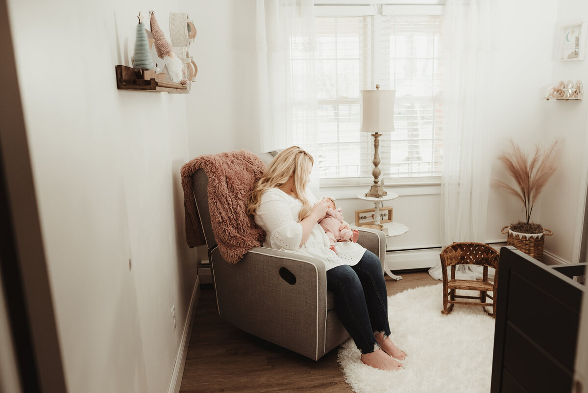 Mother rocks her newborn daughter in a light and airy nursery.