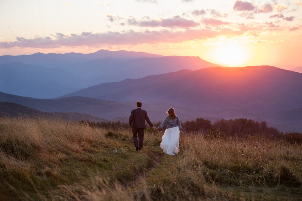 eloping couple walks hand in hand at sunset during their Max Patch elopement in NC