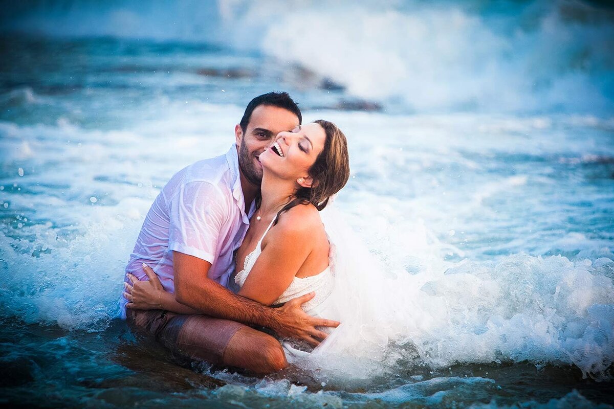 Bride and Groom fully dressed in the water laughing and hugging eachouther