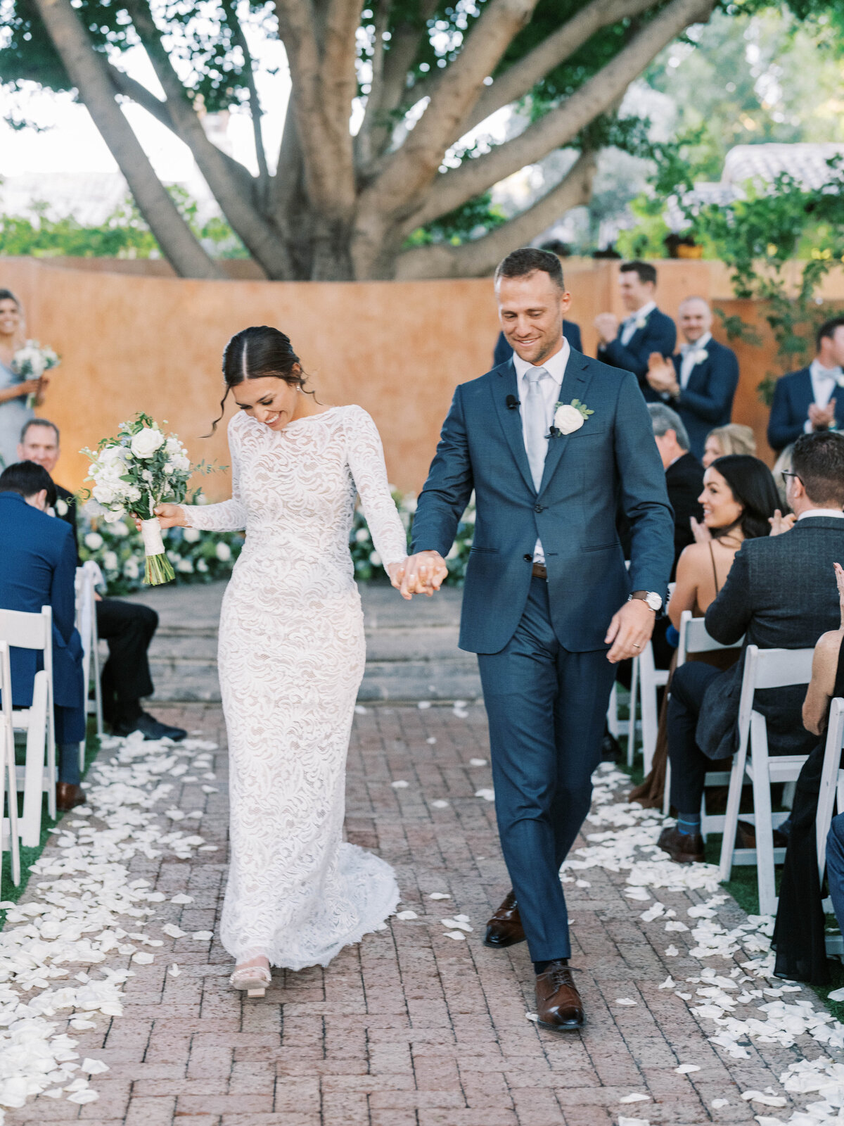 Best wedding photographer capturing a joyful just-married moment as the bride and groom walk down the aisle, surrounded by love and celebration.