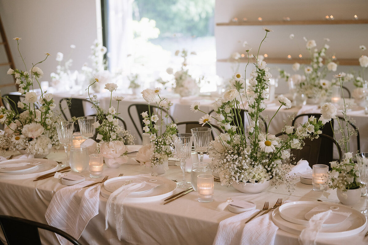 A row of modern wedding centrepieces forms a meadow of white flowers at Verger du Flanc Nord.