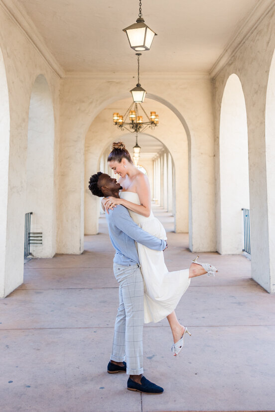man holding up fiance at balboa park san diego