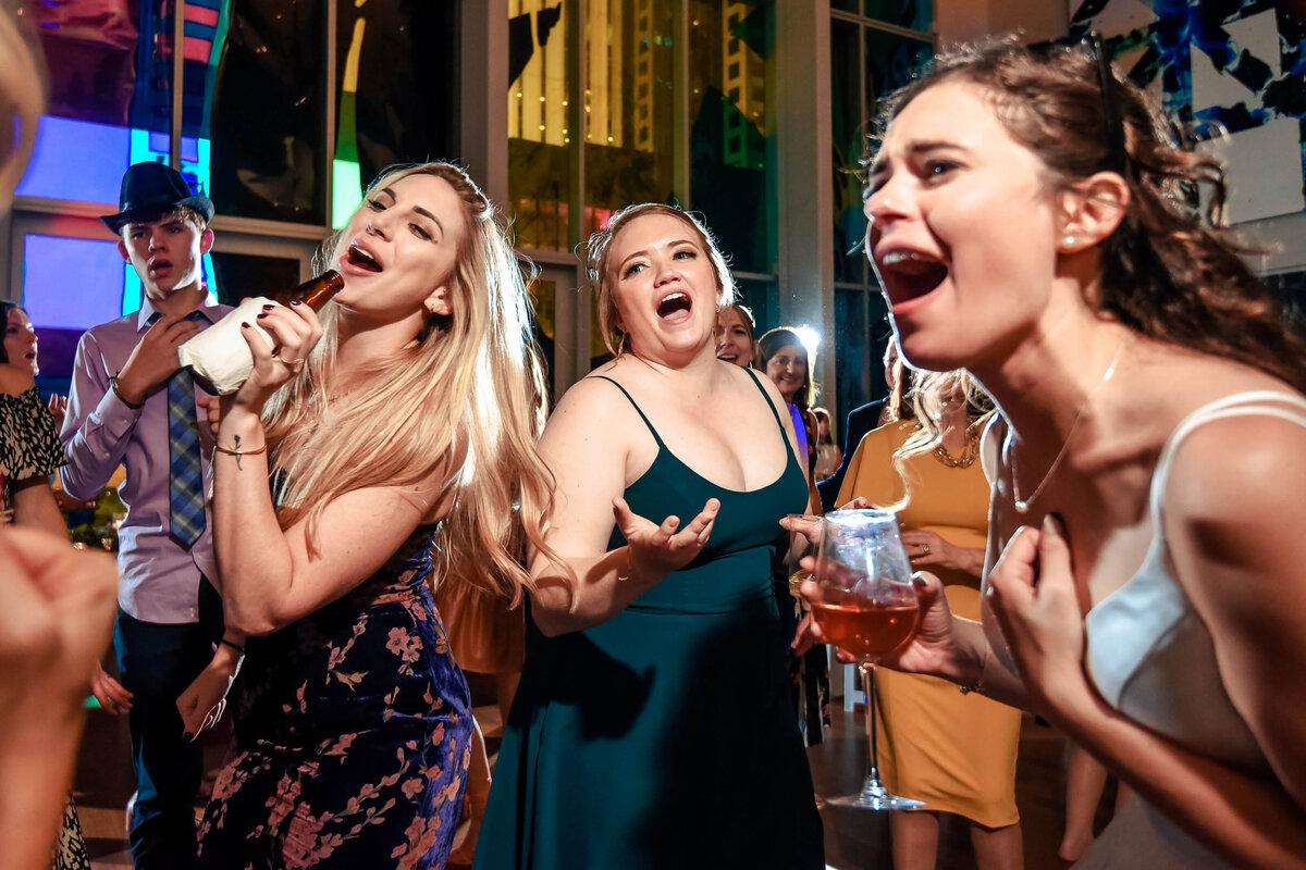 Up close photograph of a bride and her guests singing at her wedding reception at The Mint Museum Uptown by Charlotte wedding photographers DeLong Photography