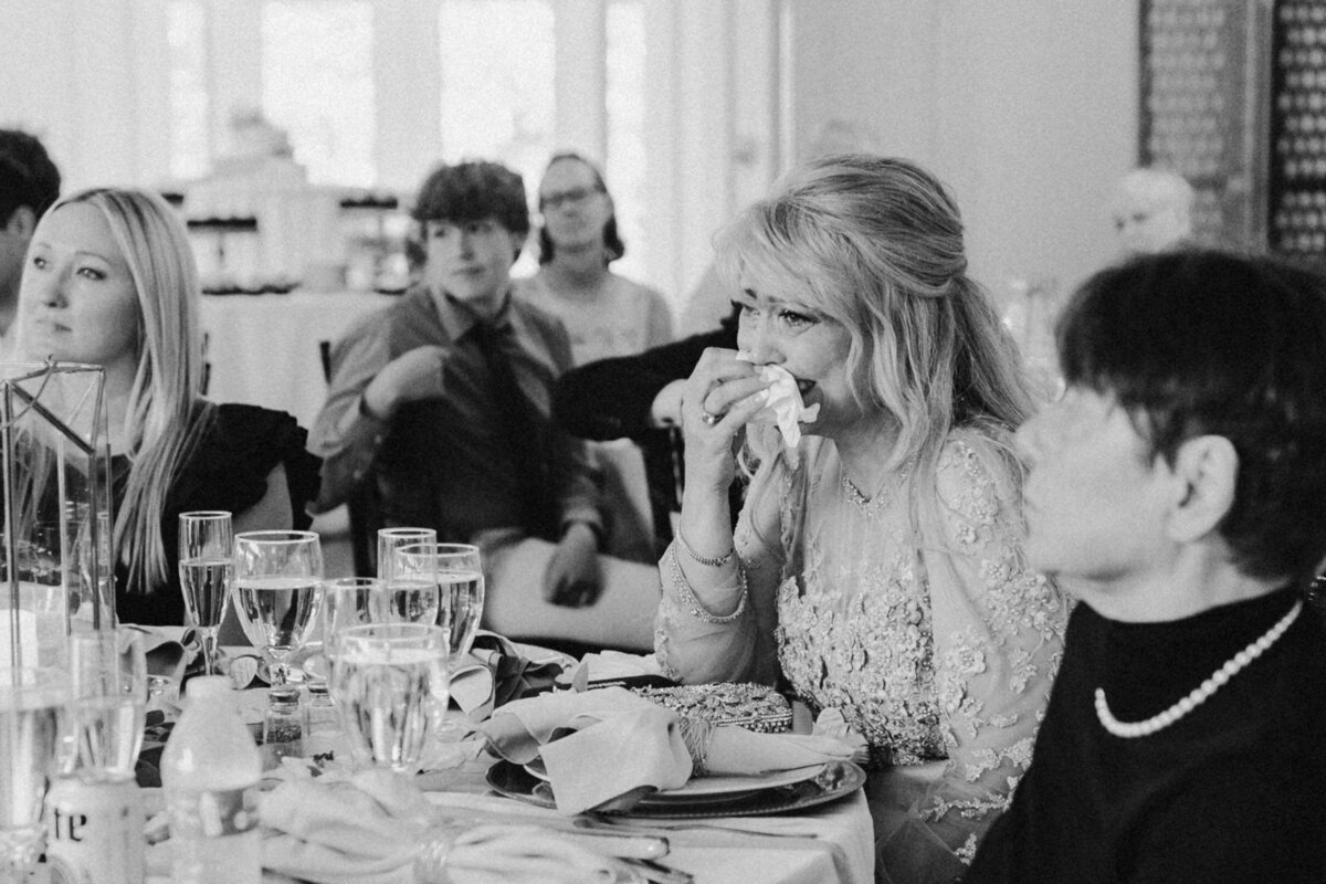 black and white photo of wedding guests while one is crying