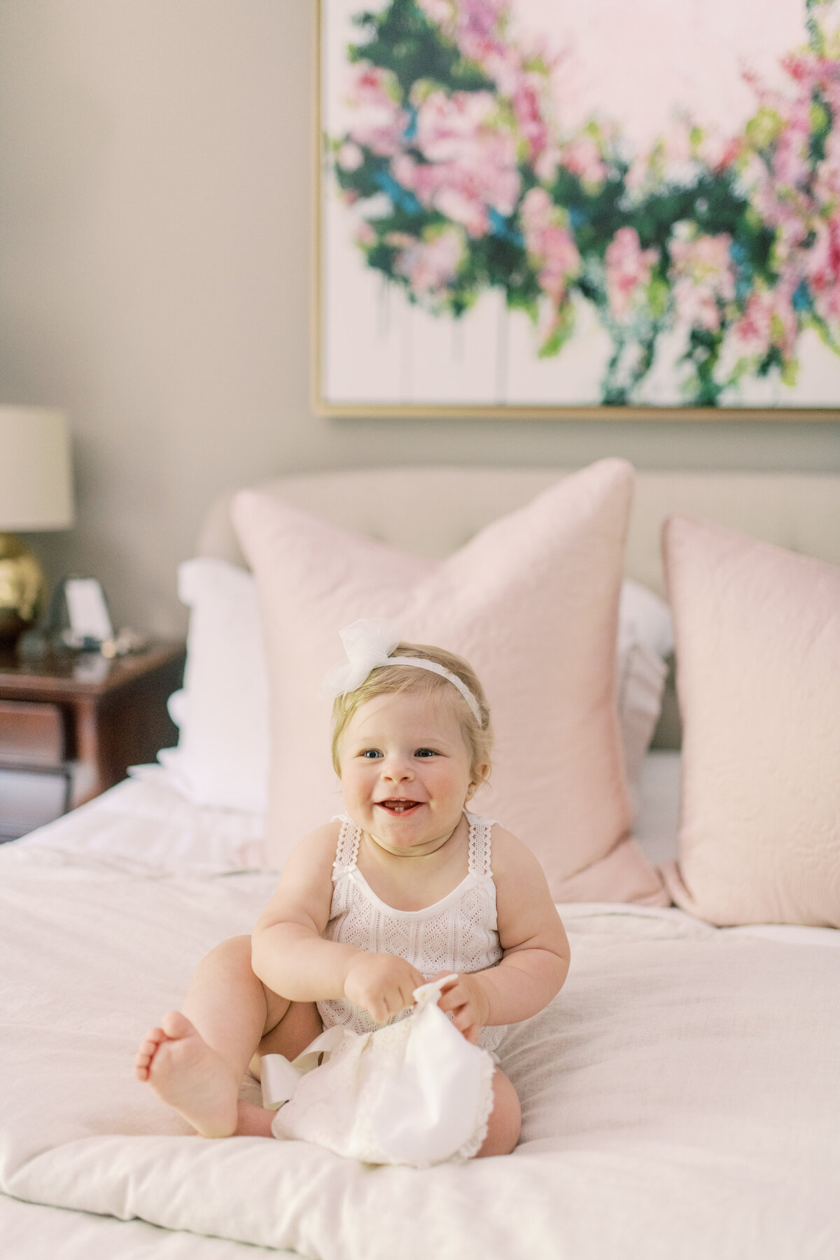 A tender, playful glimpse as baby explores the silk ribbon of her gown during family preparations.
