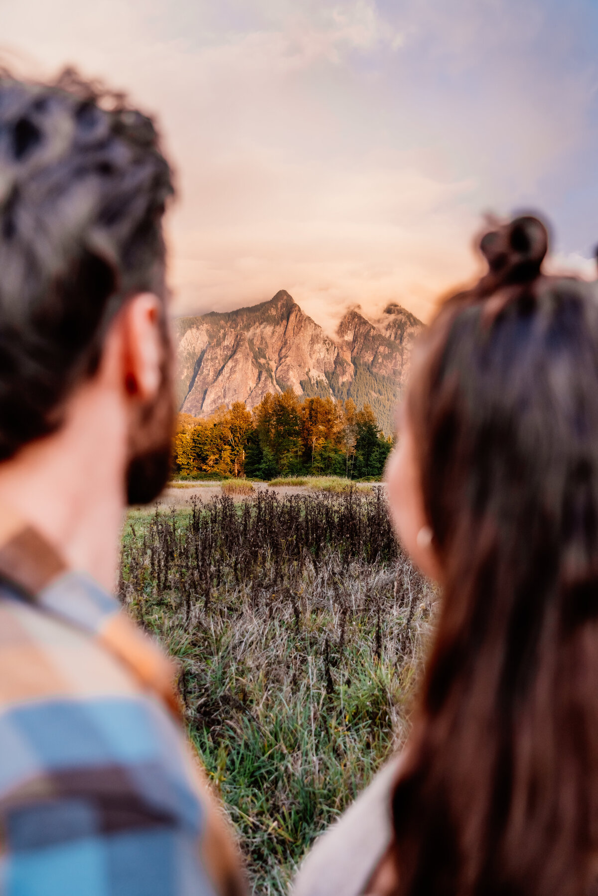 a close up of an out of focus couple with a washington mountain in the background in focus