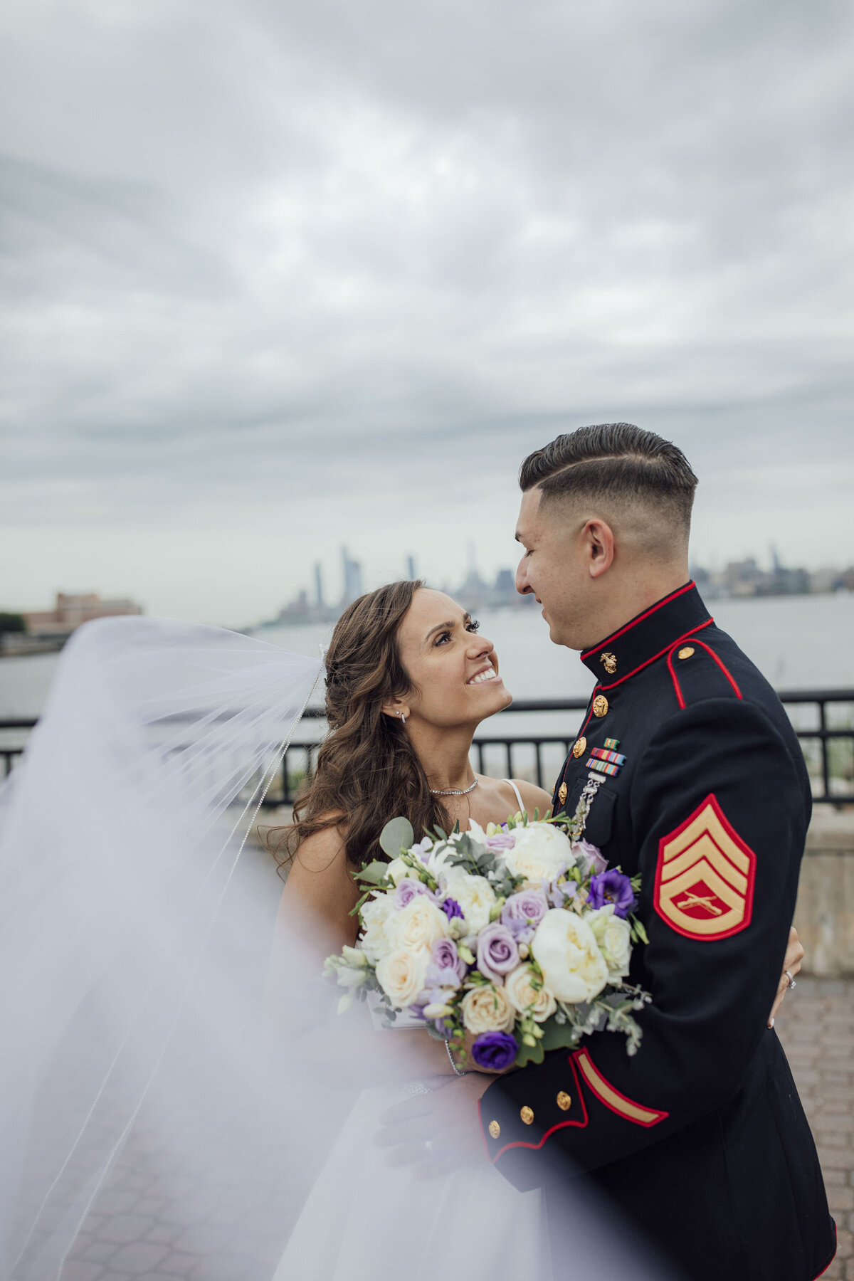 liberty-state-park-marine-groom-looking-at-bride-with-flowing-veil-nyc-skyline-jersey-city-new-jersey