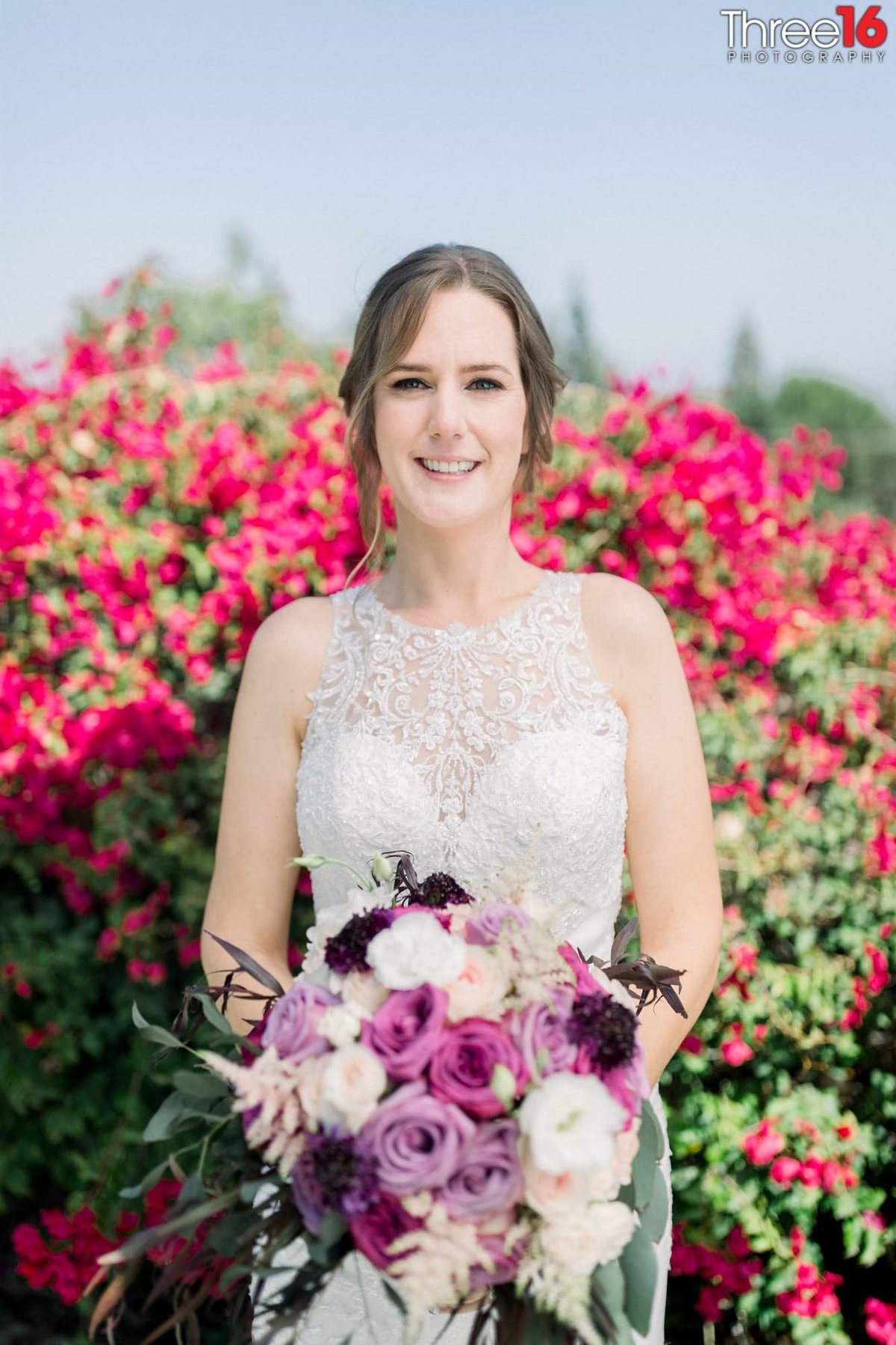Beautiful Bride poses holding her purple and white floral bouquet